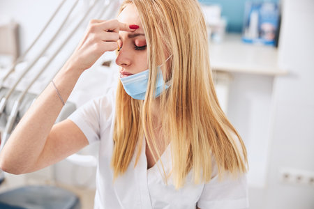 Concentrated medical worker keeping her eyes closed while trying to refresh herselfの写真素材