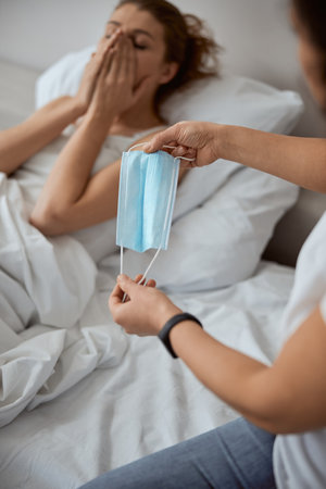 Silhouette of sick woman lying in her bed and covering mouth while coughingの写真素材
