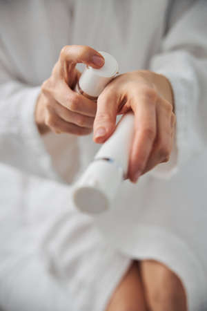 Close up of female hands holding two bottles of moisturizing hand cream