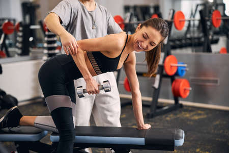 Joyful sportswoman lifting dumbbell during her trainingの写真素材