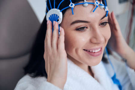Smiling attractive woman undergoing the electroencephalography procedure