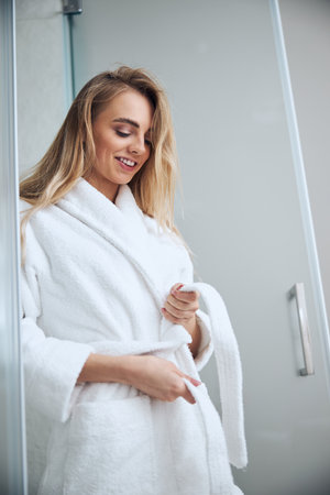 Pleased cute woman getting dressed in the bathroomの写真素材