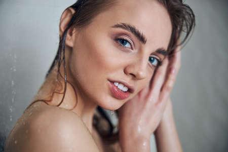 Calm naked female with wet hair looking ahead