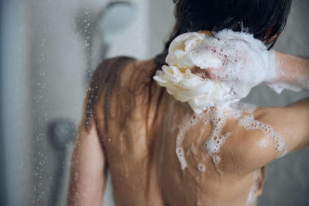 Long-haired nude young Caucasian female washing herselfの写真素材