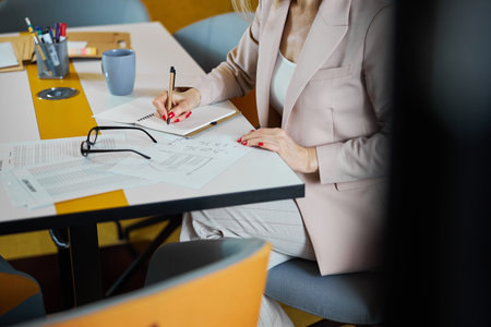 Focused photo on businesswoman making notes during workの写真素材