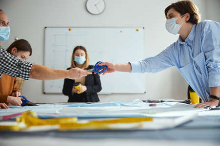 Male passing scissors to female on the rightの写真素材