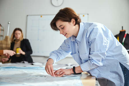 Tailor woman marking cloth with chalk piece