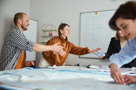 Two colleagues reaching for smartphone in tailoring teacher handの写真素材