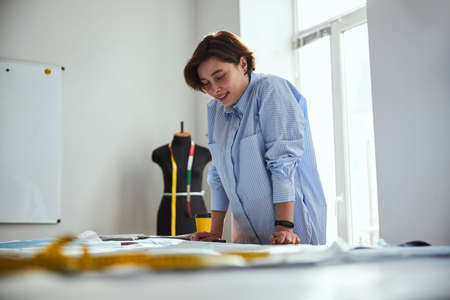 Female putting hands on the table and studying sewing patterns