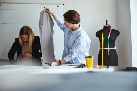 Female dress designer is spreading fabric sheet