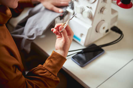 Dressmaker is showing embroidery scissors to camera