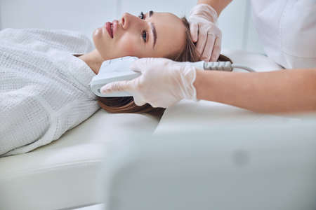 Gorgeous charming female getting face lifting in spa salon
