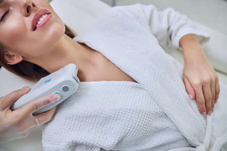 Adorable woman with cute smile and close eyes enjoying treatment procedure in spa salonの写真素材