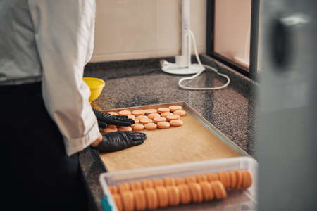 Qualified pastry cook organising crisp macarons on a baking trayの写真素材