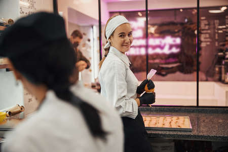 Friendly female chef posing with syringe full of icingの写真素材