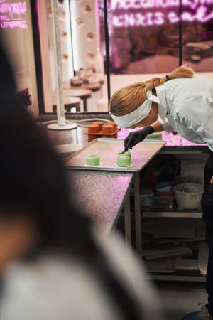 Concentrated pastry chef finishing making tasty dessertsの写真素材