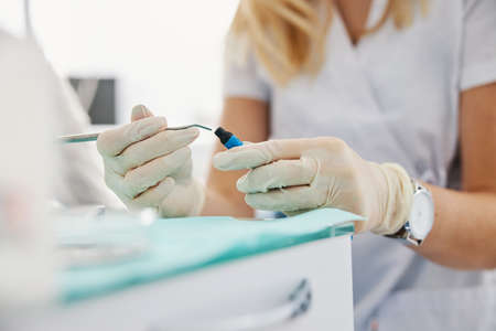 Woman reaching inside composite material bottle with dental carverの写真素材