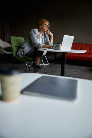Concentrated brunette female using laptop for work