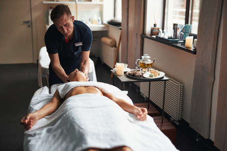 Beautiful young lady lying on massage table and relaxing at the manual therapy in health center
