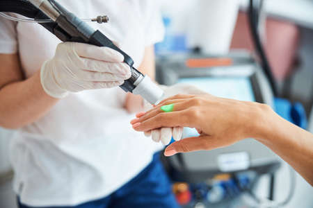 Cosmetician removing unwanted hair from female fingers