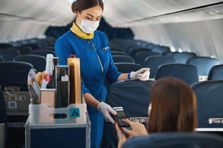 Airline stewardess holding terminal while passenger making payment