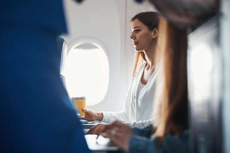 Female sitting with coffee on her plane seatの写真素材