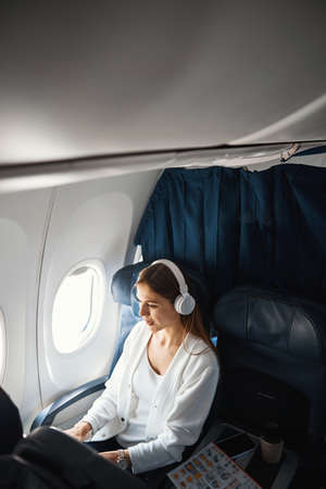 Attractive young lady listening to music in the planeの写真素材