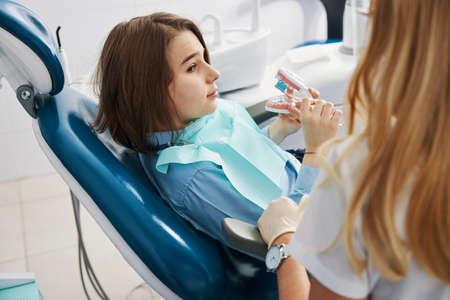 Boy watching dentist while cleaning upper teeth of dental modelの写真素材
