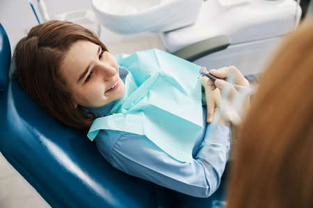 Joyful child staring at dental drill in dentist handの写真素材