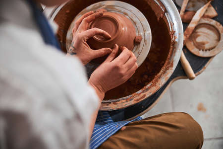 Pottery artist scratching bowl side with one hand