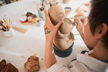 Pottery artist in process of carving animal statuette faceの写真素材