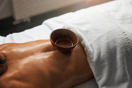 Focused image of elegant woman with towel on her body relaxing after the aroma therapy with...