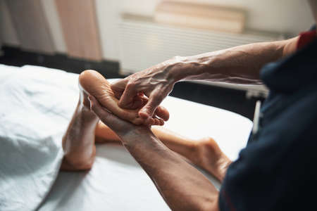Beautiful young woman lying on massage table while getting massage therapy in spa salonの写真素材
