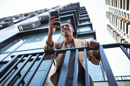 Happy male person staring at screen of telephone