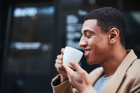 Pleased male person enjoying favorite smell of coffeeの写真素材