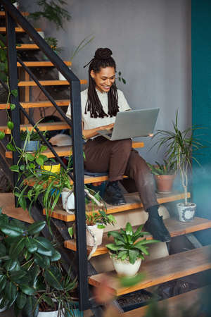 Joyous florist working on a laptop in her workshop