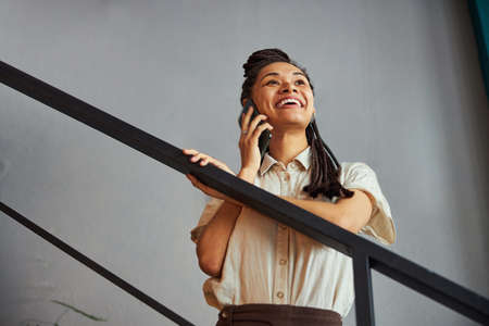 Joyous African American woman chatting on her smartphoneの写真素材