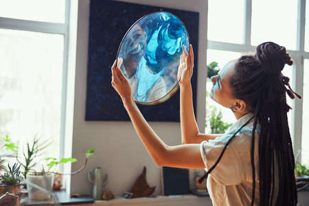 Painter holding a fluid art picture in her handsの写真素材