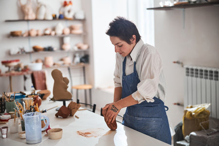 Concentrated brunette woman preparing clay for sculptingの写真素材