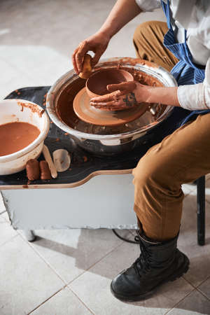 Focused photo on potter molding ceramics tableware