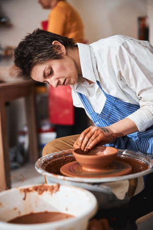 Portrait of kind potter shaping clay plateの写真素材
