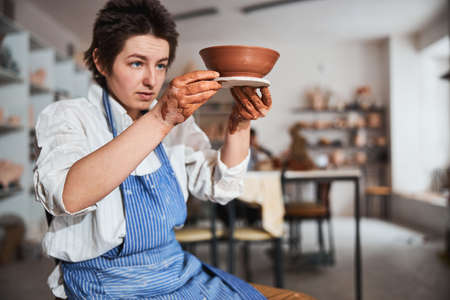 Serious ceramist staring at result of her pottery