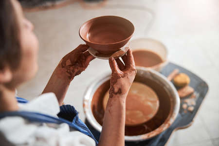 Focused photo on hands that holding clay bowl
