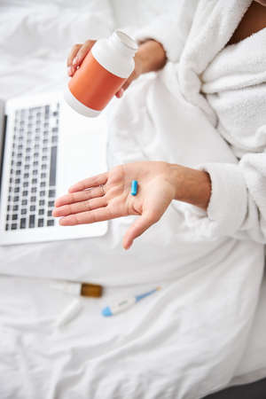 Unrecognized female showing medication in arms while sitting in room indoorsの写真素材