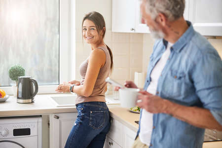 Happy cheerful female looking to her husband in the kitchenの写真素材