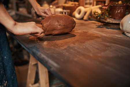 Unrecognized woman at the delicate modeling process with earthenware tool in pottery workshopの写真素材