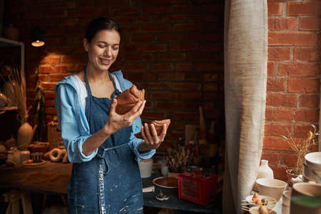 Beautiful young lady enjoy working with earthenware product in pottery studioの写真素材