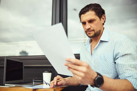 Portrait of serious man staring at paperの写真素材