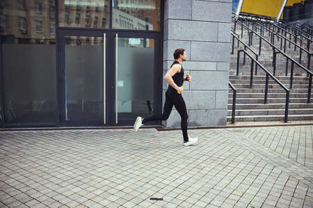 Young sportsman running near the city stadium