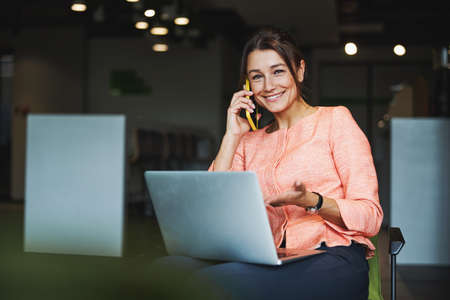 Young attractive elegant Caucasian female freelancer working online while using laptop in co-working spaceの写真素材